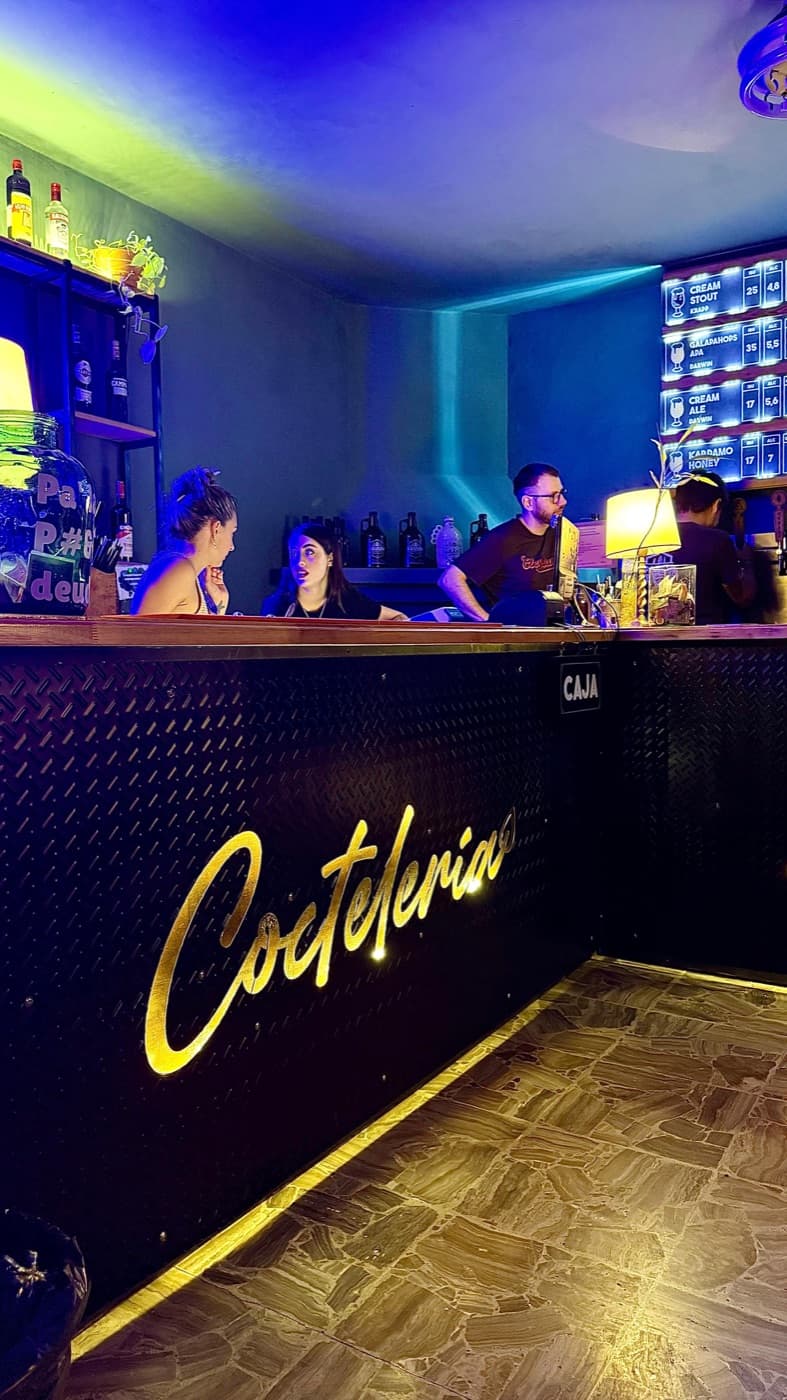 La barra de Pausen con el cartel de coctelería en dorado y la pizarra de cervezas de canilla