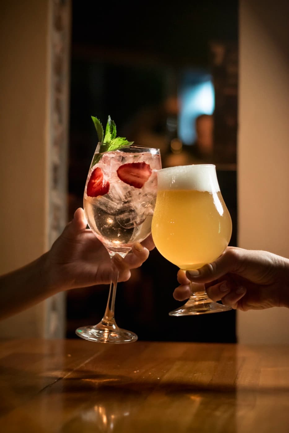 Un brindis con una cerveza artesanal tirada y un trago con frutillas