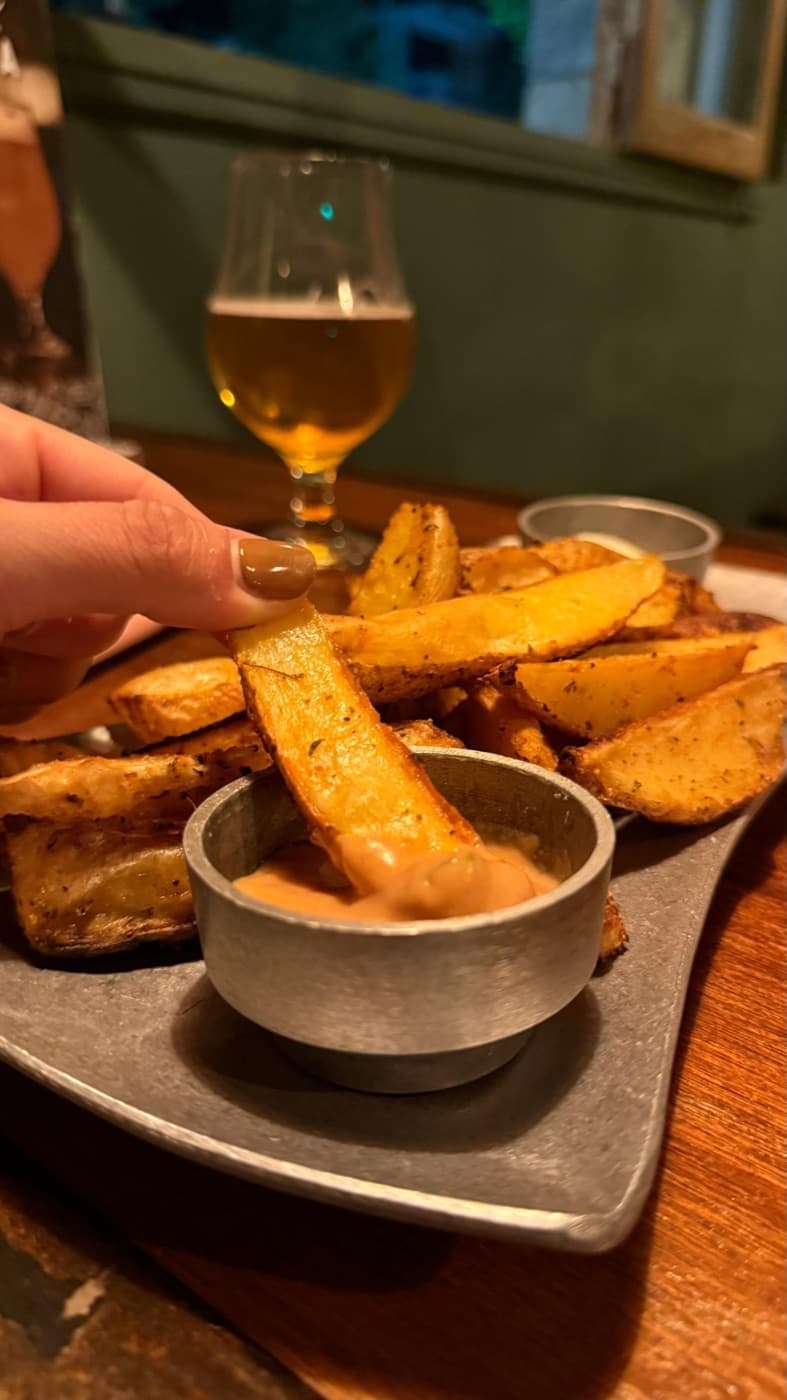 Una porción de papas con una cerveza en la mesa