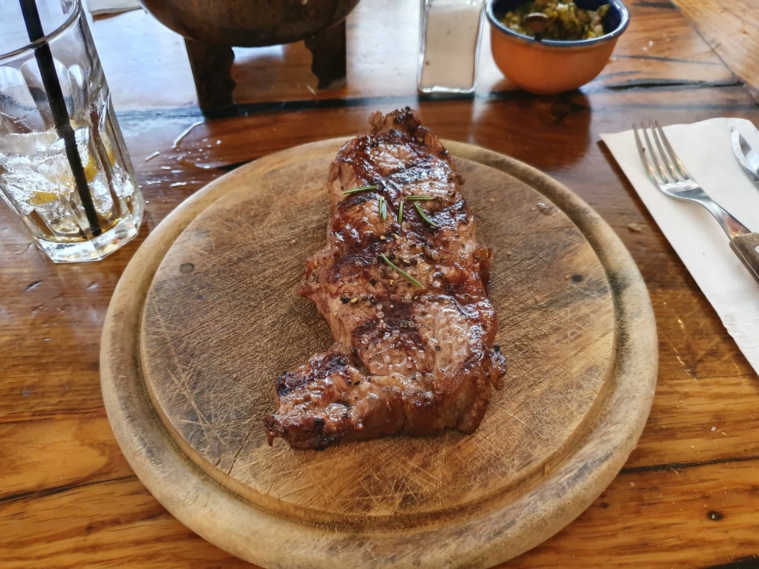 Bife de chorizo a la parrilla servido en tabla, con chimichurri